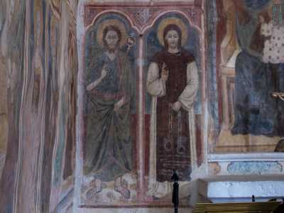 In basso si distinguono infine le figure di San Giovanni Battista che indossa pelli di animali e calzari di cuoio e di San Leonardo protettore dei carcerati, raffigurato con le catene